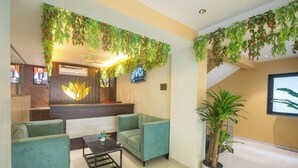 Un área de recepción con un sofá verde, una mesa de centro y una planta en maceta.