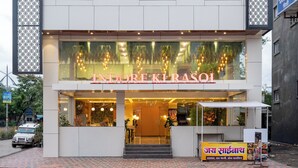 Un hotel llamado "Pravasastay" con un letrero que dice "Indore Klasoi" y un puesto de comida.