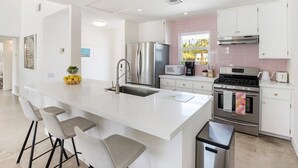 Una cocina moderna con una isla central, electrodomésticos de acero inoxidable y un ventanal con vistas.