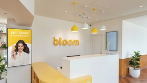 A reception area with a white reception desk, yellow pendant lights, and a large 'bloom' sign on the wall. - Bloom Boutique - Dal Lake (Srinagar)