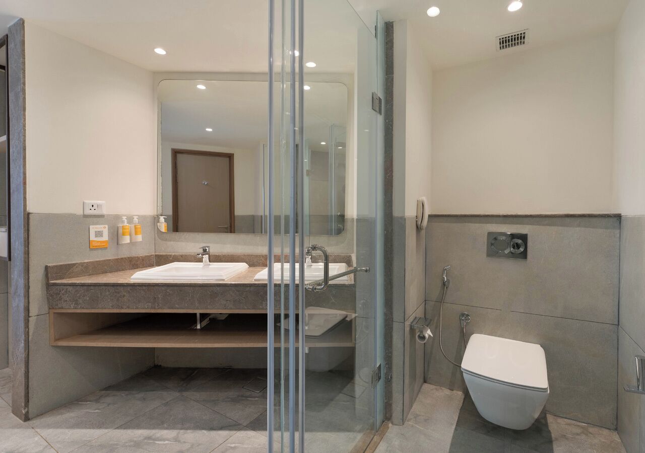 Un baño moderno con ducha de vidrio, lavabo con tocador e inodoro.