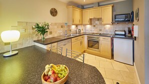A modern kitchen with granite countertops, wooden cabinets, a microwave, and a built-in oven.