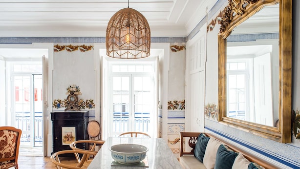 A dining area with a marble table, wicker chairs, and a sofa with cushions. - Central 3 Bedroom Apartment in Ericeira (Mafra)