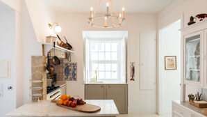 A kitchen with a marble countertop, a chandelier, and a window with a view. - Central 3 Bedroom Apartment in Ericeira (Mafra)