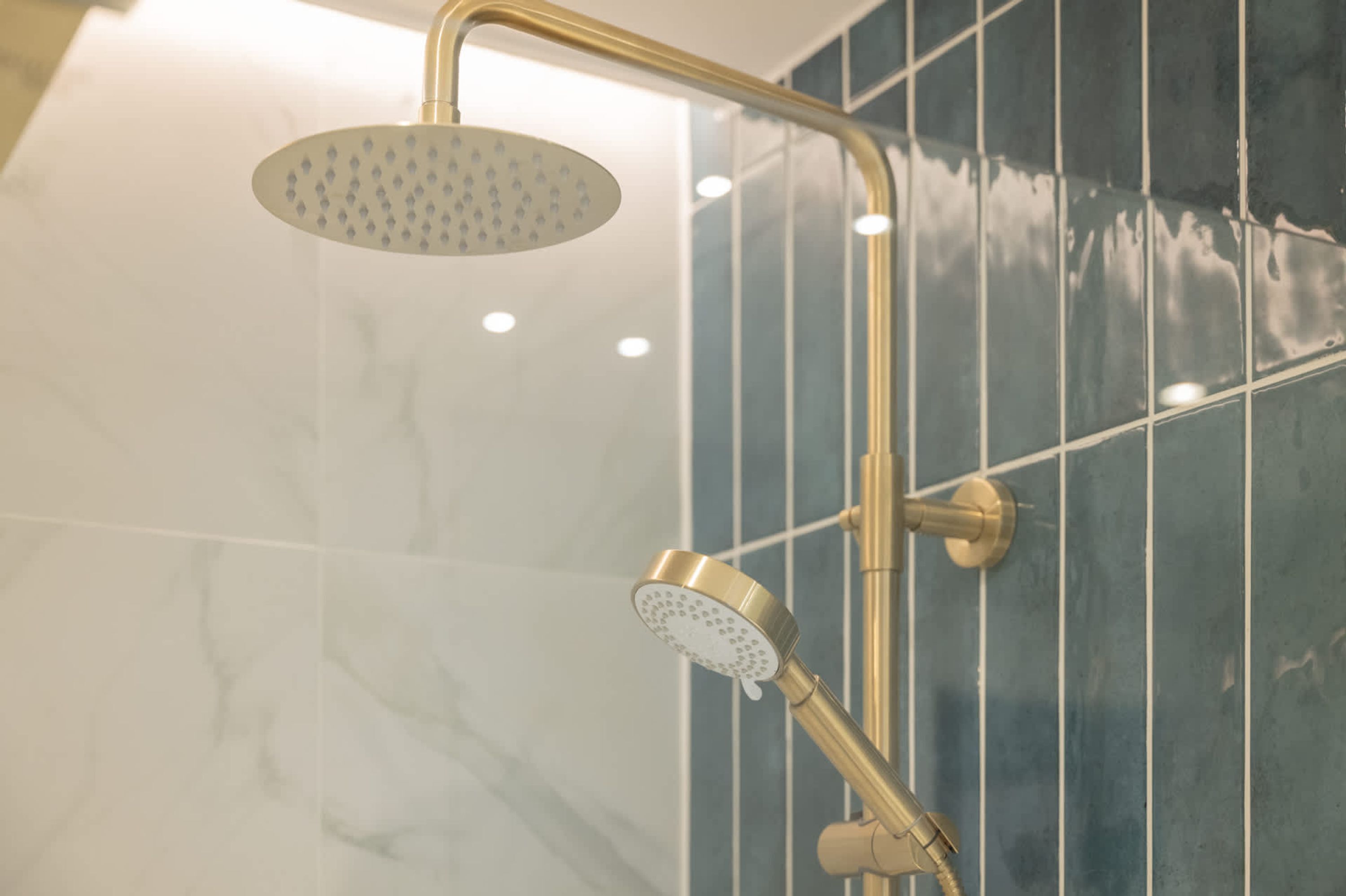 A shower with a handheld showerhead and a fixed overhead showerhead mounted on a curved metal frame.