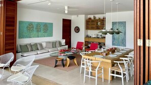 Een moderne woonkamer met een bank, salontafel en een eetgedeelte met stoelen en een houten tafel.