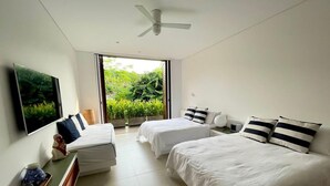 Een moderne hotelkamer met twee bedden, een flatscreen-tv en een balkon met uitzicht op groen.
