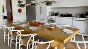 Een moderne keuken met witte kasten, een houten eiland en witte stoelen.