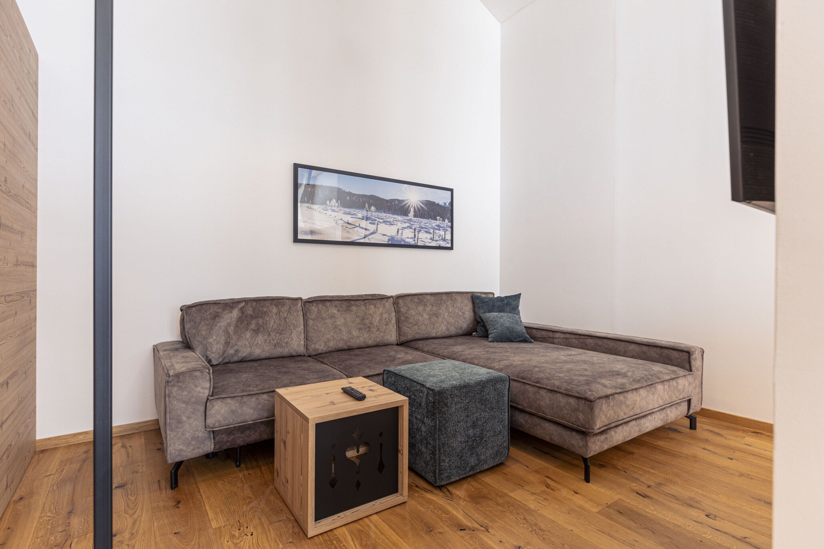 A modern living room with a sectional sofa, a small wooden side table, and a framed picture on the wall.