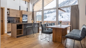 Une cuisine moderne avec des meubles en bois, un îlot central et une grande fenêtre donnant sur un paysage enneigé.