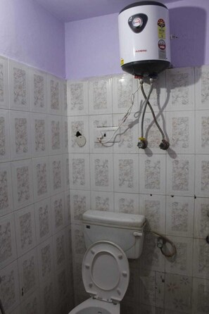 Bathroom features a toilet, wall-mounted water heater, and a floral-patterned tile wall.
