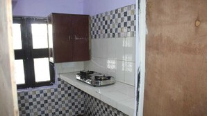 A small kitchen with a gas stove, a window, and checkered tiles on the walls.