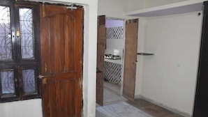 A hallway with a wooden door and a tiled wall.