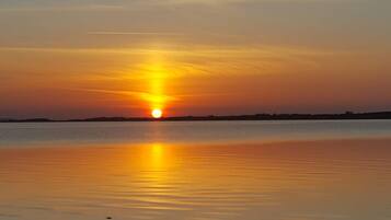 A sunset over a calm body of water with a distant shoreline.