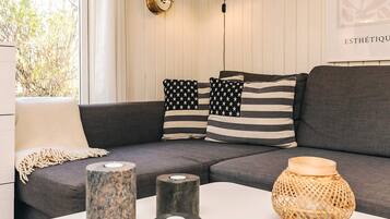 A modern living room with a grey sofa, striped pillows, and a white coffee table with decorative vases.