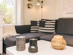 A modern living room with a grey sofa, striped pillows, and a white coffee table with decorative vases. - 6 Person Holiday Home in Nibe (Nibe)
