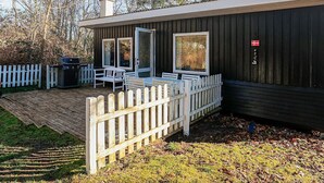 A wooden cabin with a deck, a grill, and a flag. - 6 Person Holiday Home in Nibe (Nibe)