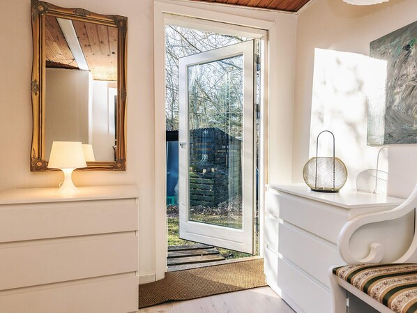 A room with a large mirror, a white chair, and a door leading outside. - 6 Person Holiday Home in Nibe (Nibe)