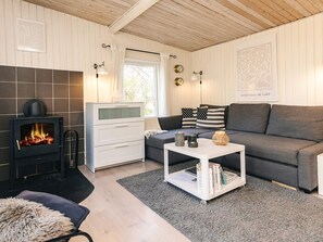 A cozy living room with a fireplace, a sofa, a coffee table, and a bookshelf. - 6 Person Holiday Home in Nibe (Nibe)