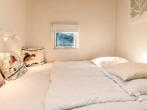 A bedroom with a bed, pillows, a window, and a wall-mounted light fixture. - 6 Person Holiday Home in Nibe (Nibe)