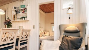 A cozy room with a wooden dining table, two chairs, a sofa, and a bookshelf. - 6 Person Holiday Home in Nibe (Nibe)