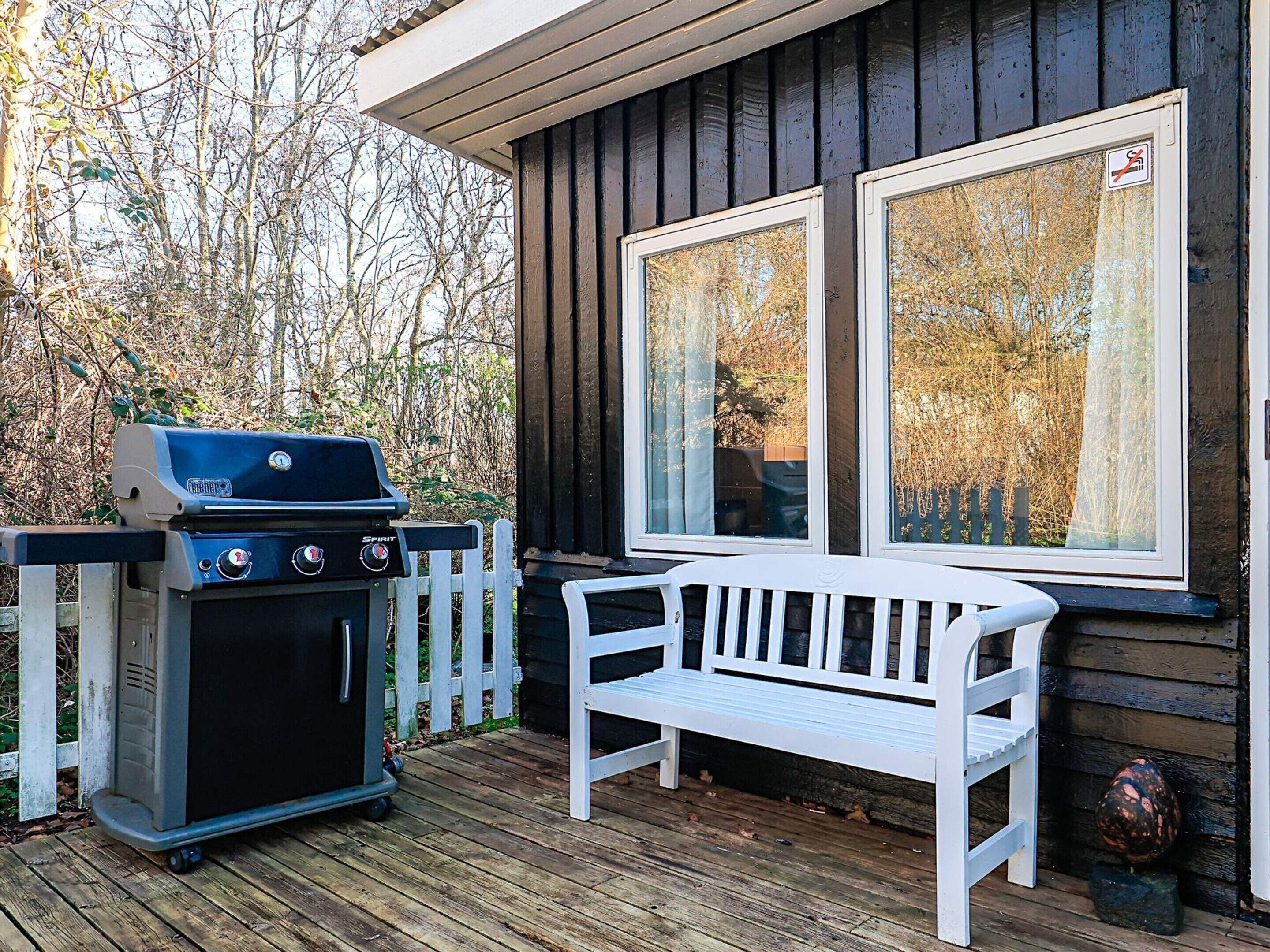 A wooden deck with a grill and a bench.