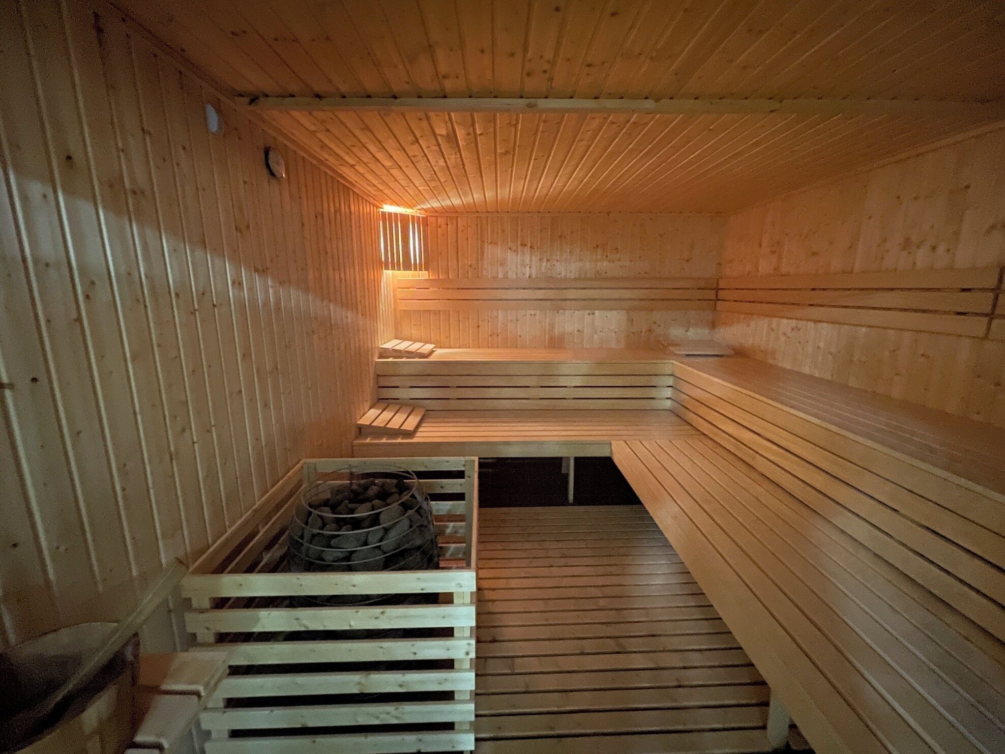 Un sauna avec des bancs en bois et un récipient rempli de pierres, probablement utilisé pour le chauffage.