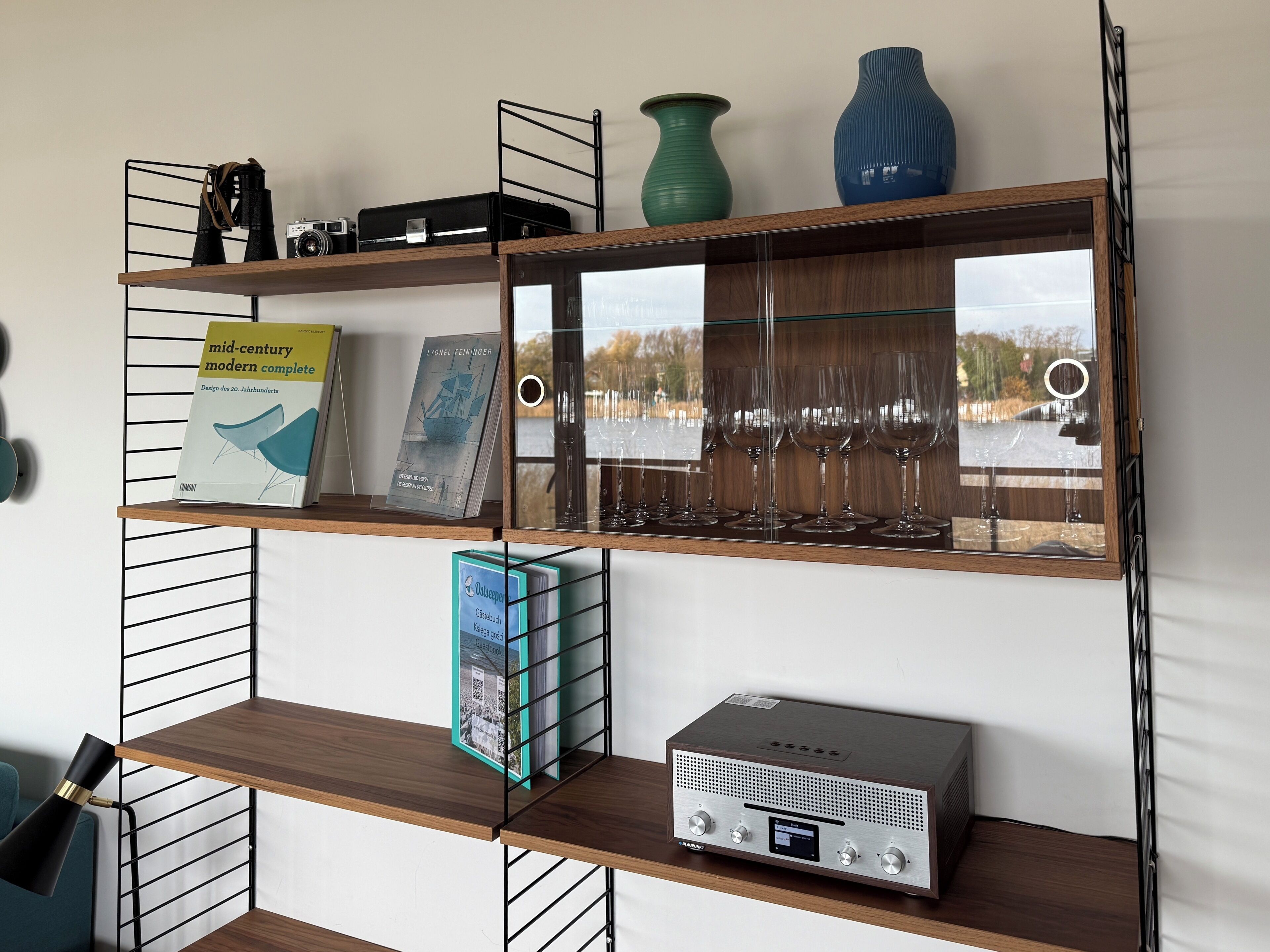 A wooden shelf unit with various items including a book, a radio, and decorative vases.