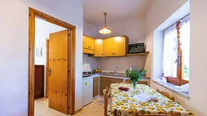 Cozinha compacta com armários de madeira, fogão a gás e área de refeições com mesa posta para dois.