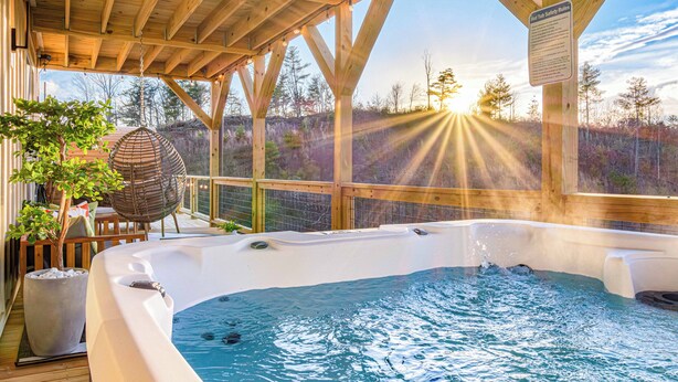 A hot tub under a wooden pergola with a view of trees and a sunset. - Game Room + Spa Stay, Sauna, Hot Tub, Dogs OK (Leicester)