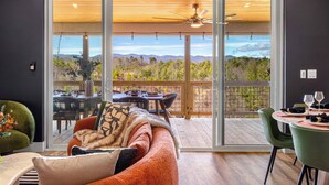 A modern living room with a large sliding glass door leading to an outdoor deck. - Game Room + Spa Stay, Sauna, Hot Tub, Dogs OK (Leicester)