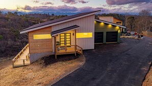 A two-story house with a wooden exterior, a covered porch, and a garage. - Game Room + Spa Stay, Sauna, Hot Tub, Dogs OK (Leicester)