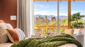 A bedroom with a large window overlooking a mountainous landscape. - Game Room + Spa Stay, Sauna, Hot Tub, Dogs OK (Leicester)