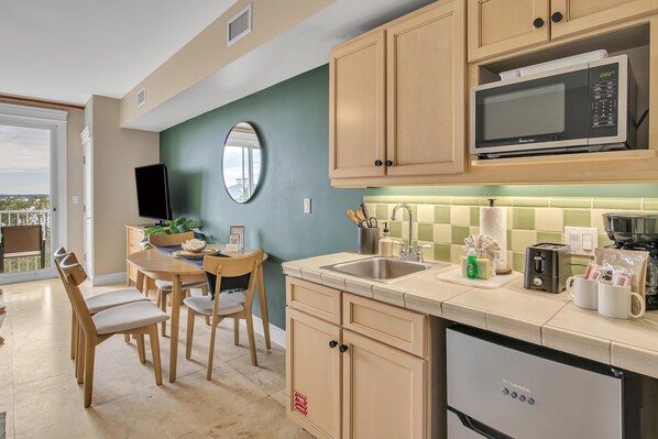 Una cocina moderna con armarios de madera, un microondas y un fregadero. Hay una zona de comedor con una mesa y sillas.