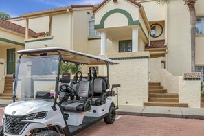 Ein Golfwagen vor einem Gebäude mit Balkon, Treppen und einem Schild mit Nummern.