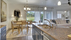 Cocina moderna con encimera de granito, pileta de acero inoxidable y mesa de comedor de madera.