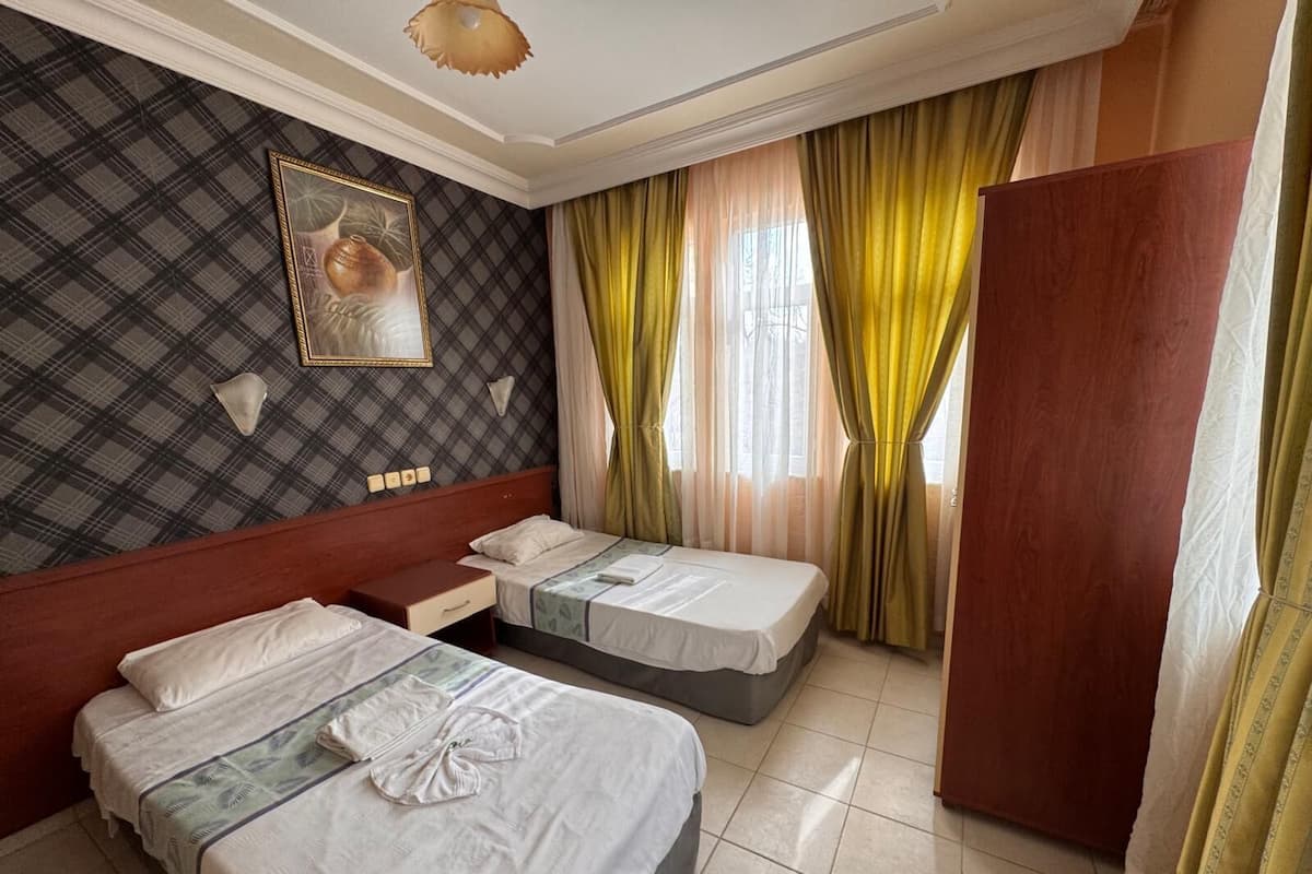 Habitación de hotel con dos camas, un espejo grande y un cuadro en la pared.