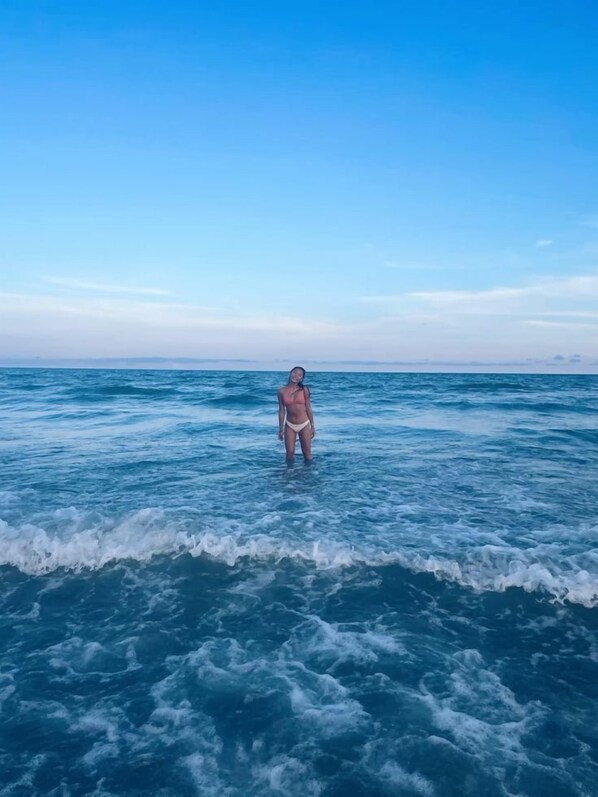A person standing in the ocean with waves around them.