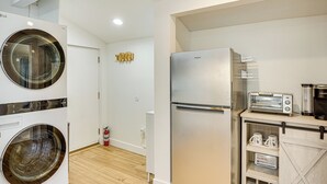 A modern kitchen with a stainless steel refrigerator, a built-in toaster, and a wooden cabinet with storage. - 3 Mi to Angel Stadium: Cozy Studio w/ Patio! (Santa Ana)