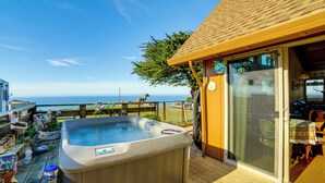 Ein Whirlpool auf einer Holzterrasse mit Blick auf den Ozean.