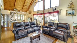 Ein geräumiges Wohnzimmer mit Ledersofas, einem Holztisch und großen Fenstern mit Blick ins Freie.