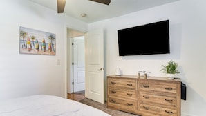 Ein Schlafzimmer mit Bett, einem Holzschrank, einem Flachbildfernseher und einem Bild an der Wand.