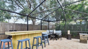 Eine Außenpatio mit einer Holztheke, blauen Barhocker und einem Tisch mit Stühlen.