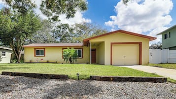 A single-story house with a garage, a well-maintained lawn, and a gravel driveway.