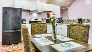 A modern kitchen with white cabinets, a black refrigerator, and a dining table set with placemats.