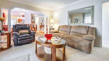 A living room with a brown leather sofa, a black leather armchair, and a round wooden coffee table.