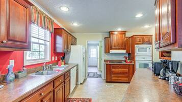 A kitchen with wooden cabinets, a granite countertop, a refrigerator, a microwave, and a coffee maker.