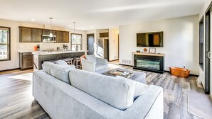 A modern living room with a grey sofa, a coffee table, and a fireplace. - Golf, Hike & Boat: Home w/ Fire Pit in Friendship (Friendship)