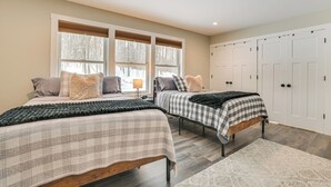 A bedroom with two beds, a large window with blinds, a wardrobe, and a rug. - 22 Mi to Boyne Mountain: Home w/ Fire Pit! (Petoskey)