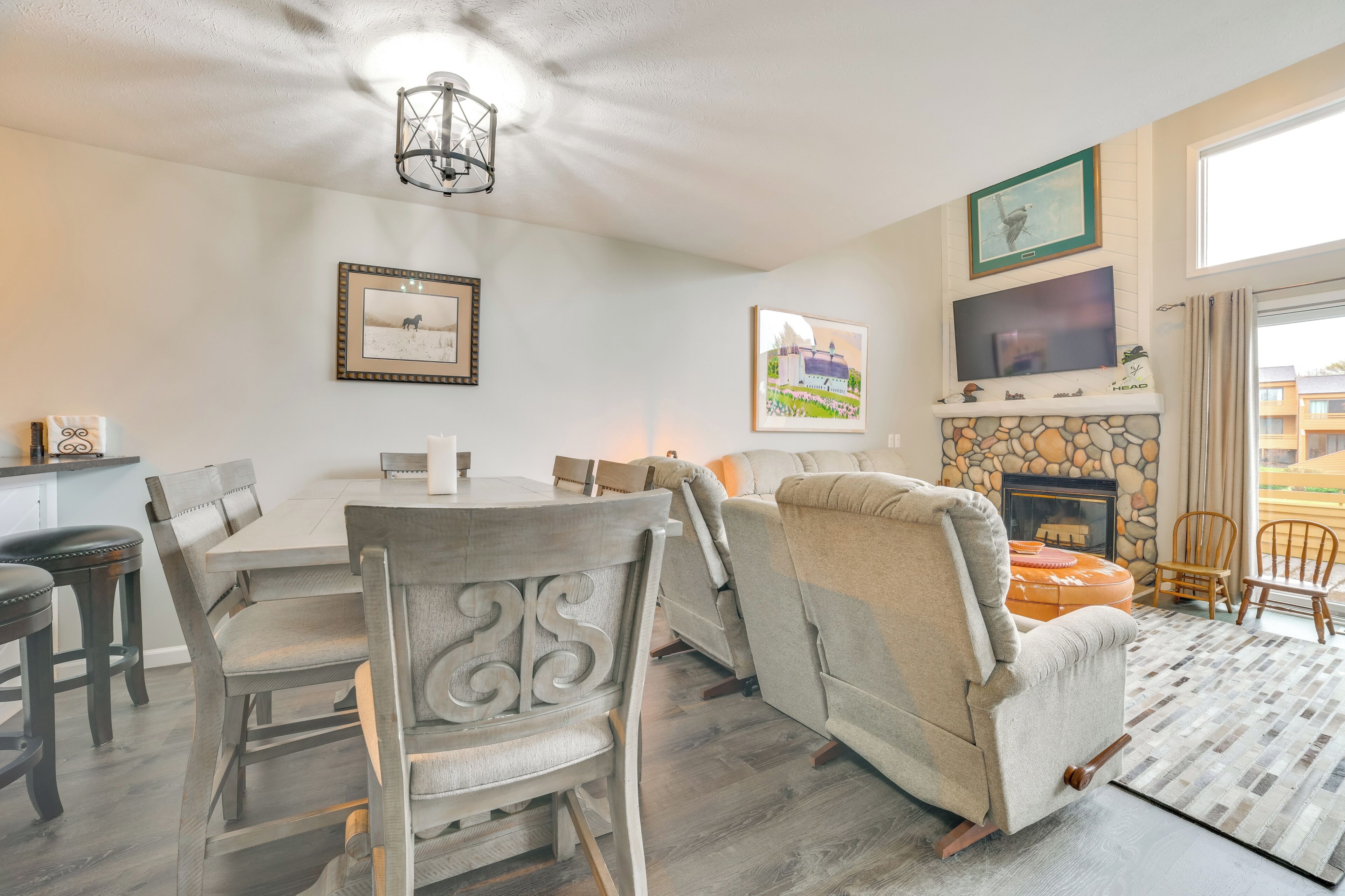 A dining area with a round table and chairs, a fireplace, and framed artwork on the walls.